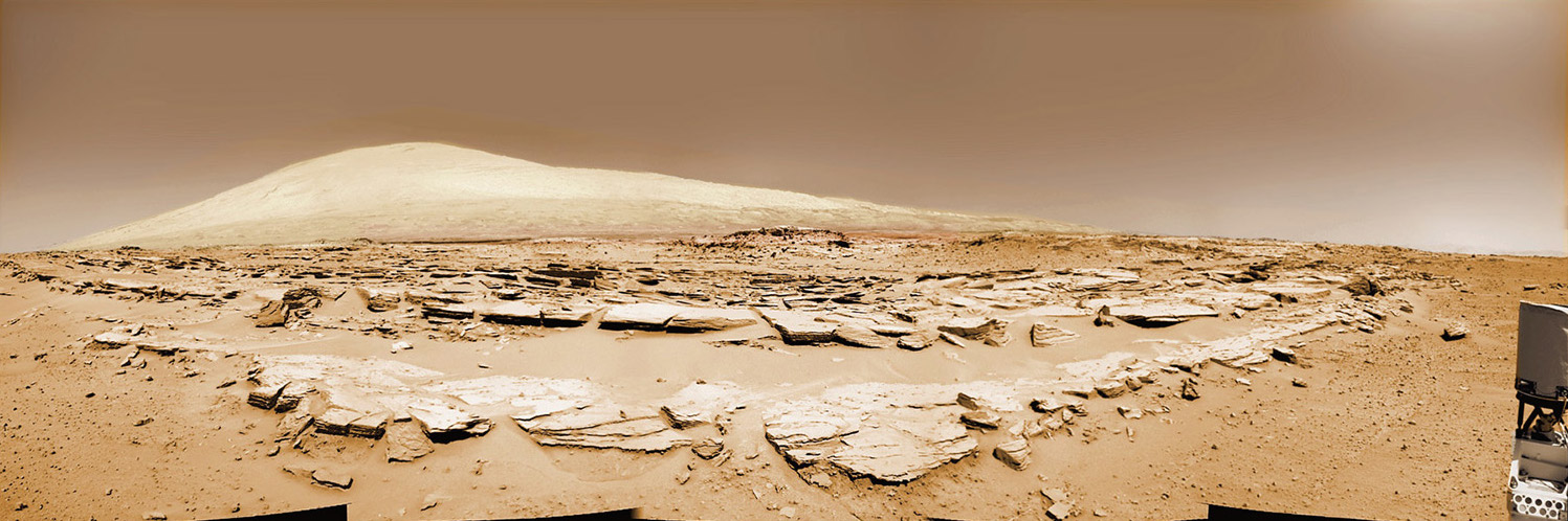 Martian landscape scene with rows of striated rocks in the foreground and spectacular Mount Sharp on the horizon. NASA’s Curiosity Mars rover paused mid drive at the Junda outcrop to snap the component images for this colorized navcam camera photomosaic on Sol 548 (Feb. 19, 2014) and then continued traveling southwards towards mountain base. Image: NASA/JPL-Caltech/Marco Di Lorenzo/Ken Kremer